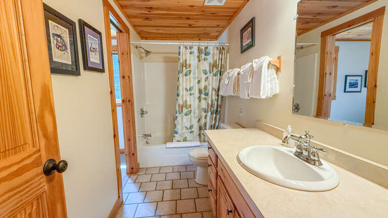 Step into your private bath with warm wood ceilings and fresh towels waiting. The shower-tub combo and bright vanity make mornings easy and relaxing.