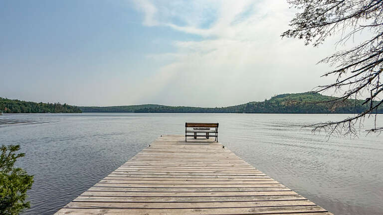 A private dock stretches over calm lake waters, offering peaceful access to the shoreline and surrounding natural beauty.