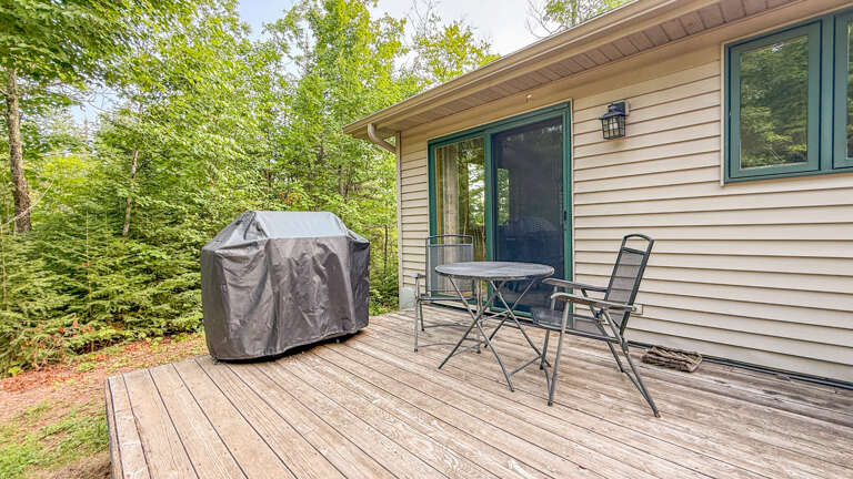 The vacation rental features an inviting outdoor deck nestled among lush forest surroundings, offering a peaceful retreat with al fresco dining space and BBQ facilities for your meals.