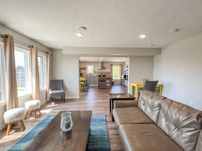 Spacious Living Area With Sleek Sofas And Wooden Floors, Leading To An Integrated Kitchen