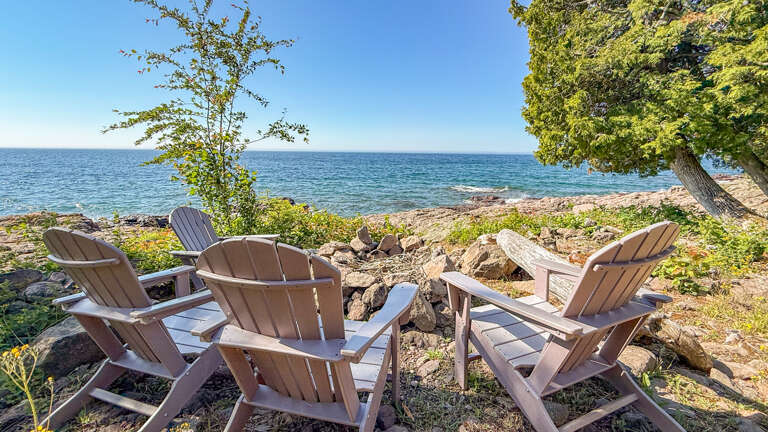 Picture yourself settling into these waterfront Adirondack chairs, waves lapping at the rocky shore just steps away. Your own private retreat by the water's edge.