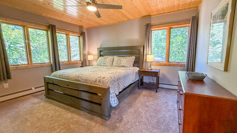 Wake up to lush forest views from your cozy bedroom, where natural light and rustic wood accents create a peaceful mountain retreat.