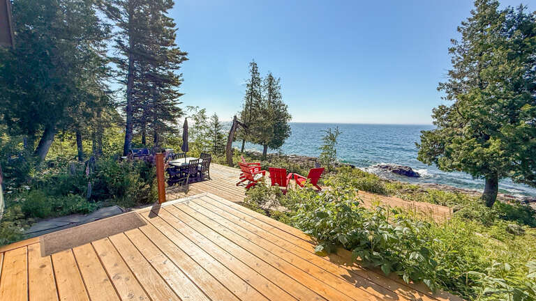 This breathtaking waterfront property offers direct access to pristine shoreline with stunning sea views framed by evergreen trees and lush coastal gardens.