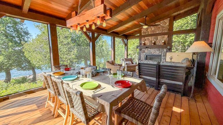 Gather around this inviting outdoor dining area, where rustic charm meets lakeside serenity. With a cozy stone fireplace and open-air design, you'll savor meals surrounded by nature's beauty.