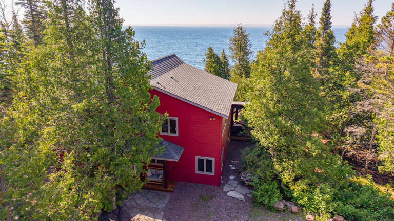 A lakeside retreat surrounded by tall pines and greenery, offering peaceful seclusion with water views.