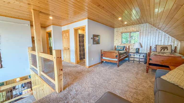 Your upstairs loft offers a cozy retreat with two inviting beds, natural wood details, and a soft, neutral palette—perfect for unwinding after a day of adventure.