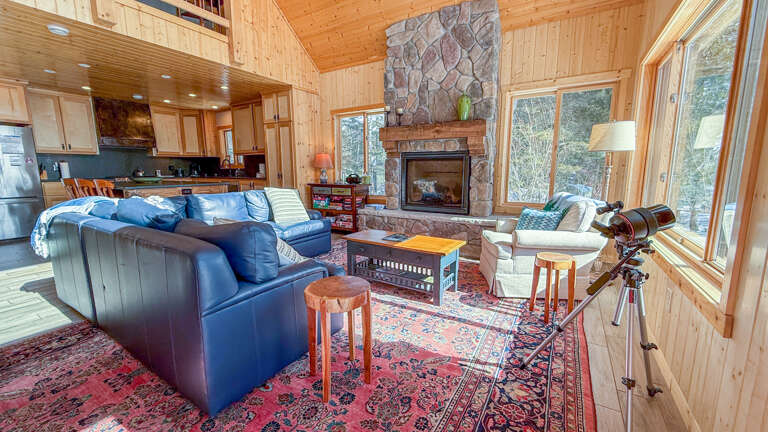 Cozy up in this stunning open-concept space where rustic charm meets modern comfort, complete with stone fireplace and panoramic forest views.