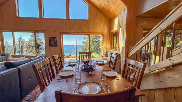 Gather around the dining table and soak in the stunning lake views through floor-to-ceiling windows. The warm wood interiors and open layout create a cozy yet spacious retreat where you can relax and reconnect.