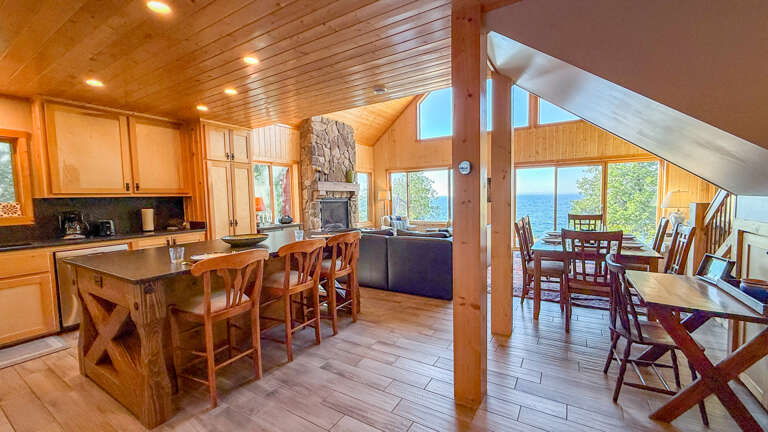 Gather with loved ones in this warm, open-plan space where your kitchen flows into cozy dining areas and a fireside living roomâall framed by stunning lake views through soaring windows.