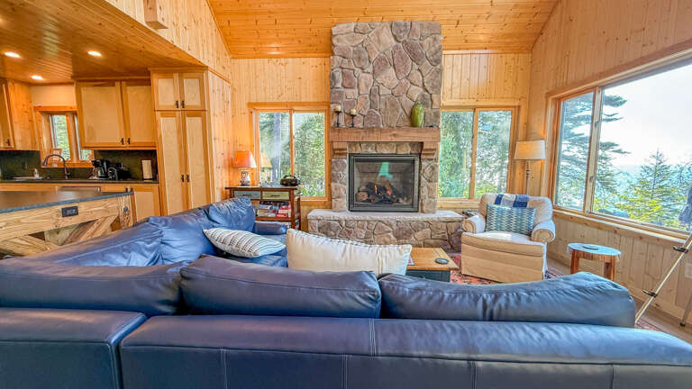 Gather around the stone fireplace in this warm, wood-paneled retreat where lake views through floor-to-ceiling windows make every moment feel special.