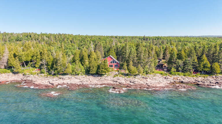 This secluded waterfront property sits peacefully along the pristine shoreline, surrounded by lush evergreen forest. A perfect retreat where land meets crystal-clear water.