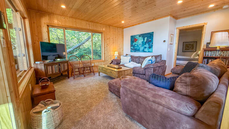Sink into plush leather sofas and gaze out at lush forest views through expansive windows. Your cozy retreat features warm wood ceilings and a relaxed atmosphere perfect for unwinding after exploring.