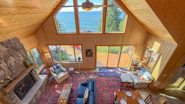 Stunning lake views frame your bright, open living space, where soaring windows flood the room with natural light. Curl up by the stone fireplace or relax on plush seating while taking in the serene water beyond.