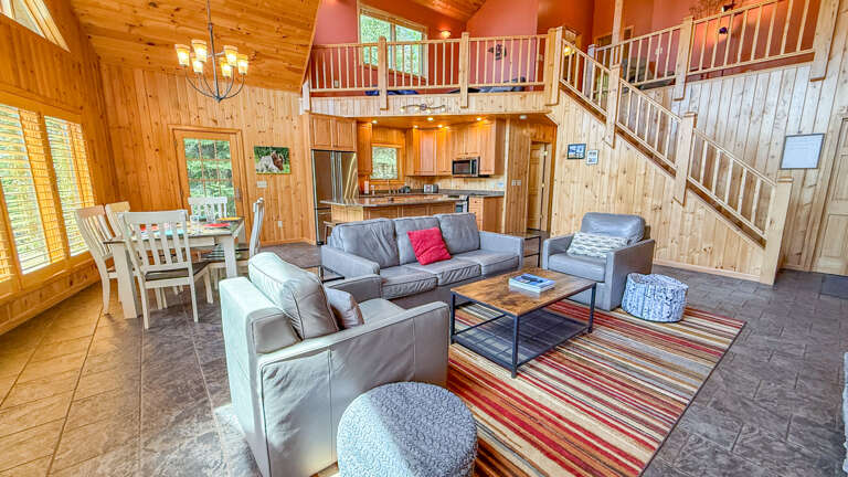 Curl up in the inviting living room where vaulted ceilings and warm wood surround you, or gather around the dining table for meals with loved ones in this open, sunlit space.