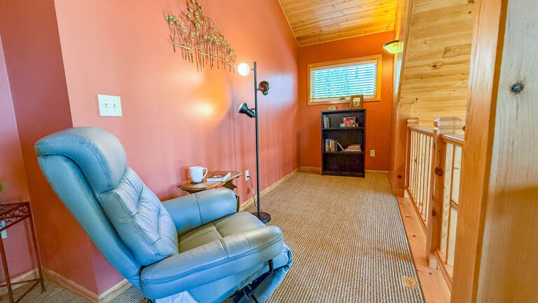 Settle into this cozy reading nook with vaulted ceilings and soft natural light streaming through the window. Your perfect spot to unwind with a book and warm cup of coffee.