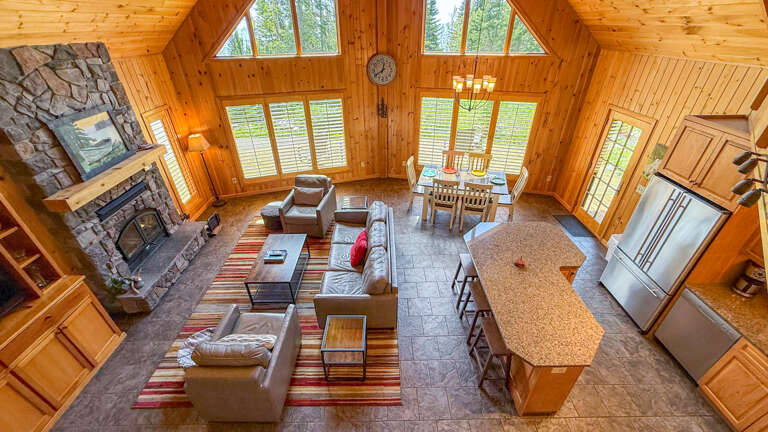 Soak in the soaring ceilings and warm wood glow of this open-concept retreat, where natural light floods your living, dining, and kitchen spaces, and cozy evenings begin by the stone fireplace.