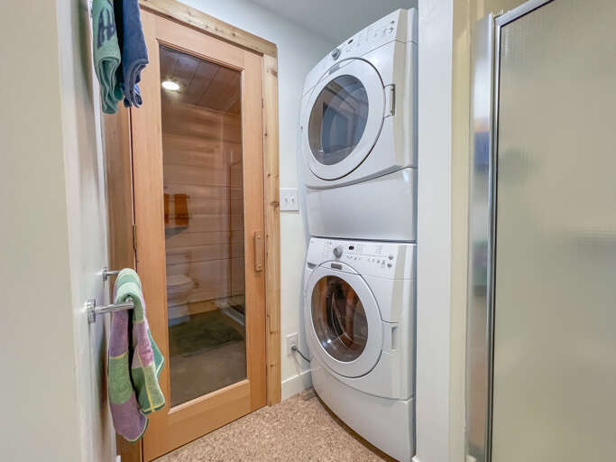 This bathroom features a walking shower, washer and dryer, and a sauna