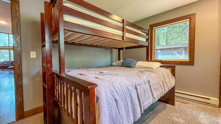 Your cozy sleeping nook features a sturdy bunk bed with natural light streaming through the window, offering a peaceful retreat after a day of adventure.