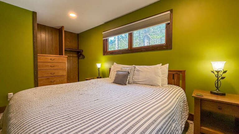 Drift off in this serene bedroom with its plush bedding, warm wood furnishings, and soft natural light from the garden-facing window. Your restful escape awaits.