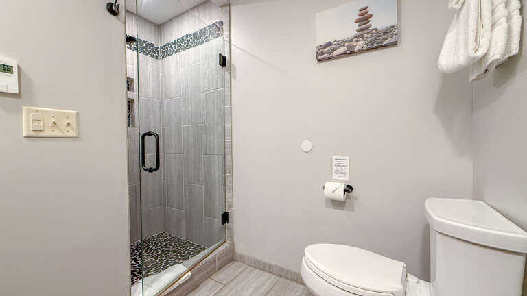 Refresh in a sleek, modern bathroom with a beautifully tiled walk-in shower featuring decorative mosaic accents and fluffy towels waiting for you.