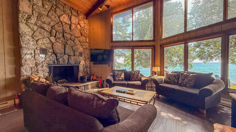 Sink into plush seating and let the stunning lake views steal your attention. Warm wood tones and a stone fireplace create the perfect backdrop for your lakeside retreat.