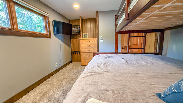 Unwind in your cozy bedroom with warm wood accents, a plush bed, and treetop views. Climb up to the loft for extra sleeping space or a quiet retreat.