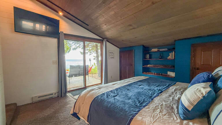 Wake up to the soft sound of waves and step directly onto your private deck. This spacious bedroom invites you to unwind with lake views framed perfectly from bed.