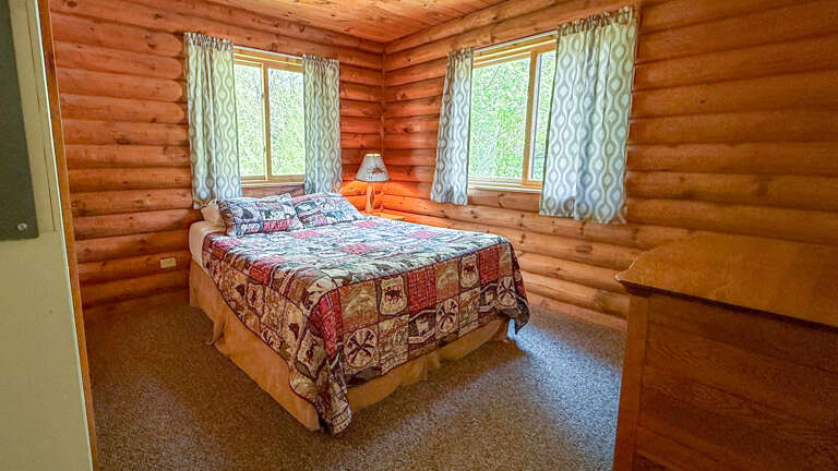 Drift off surrounded by warm log walls and forest views in your cozy bedroom retreat with handmade quilt charm.