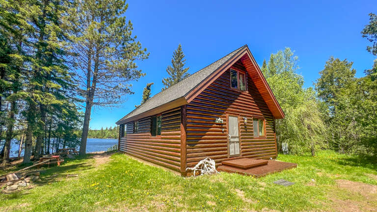 Rustic log cabin retreat nestled among towering pines with pristine lakefront access and peaceful wilderness surroundings.