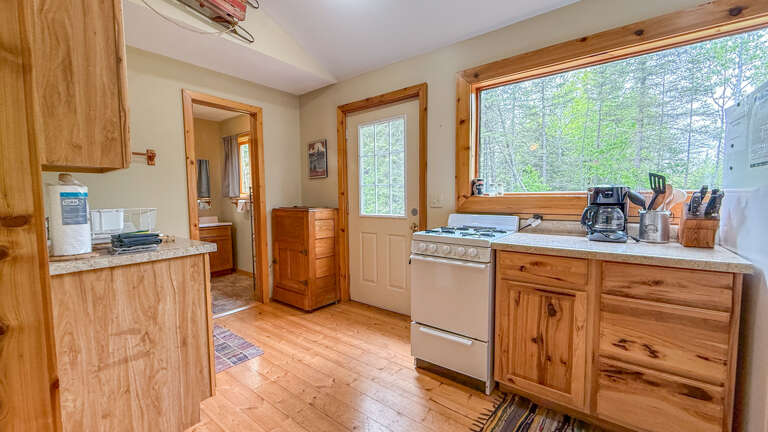 Your rustic kitchen features warm wood cabinetry, granite counters, and forest views that make cooking feel like a woodland retreat.