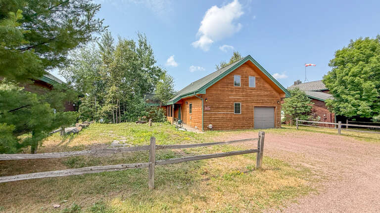 A charming wood-sided cabin with a green roof sits nestled among trees, offering a serene retreat surrounded by natural beauty and peaceful privacy.