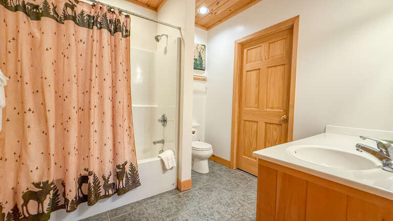 Freshen up in your private bathroom with a relaxing tub-shower combo and modern fixtures. The warm wood accents and rustic charm make it feel like a cozy mountain retreat.