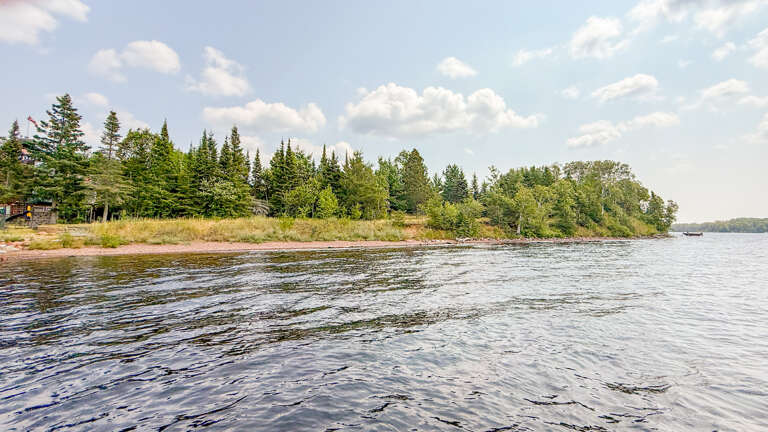 A serene lakefront property surrounded by evergreen forest and natural shoreline, offering peaceful waterside tranquility.