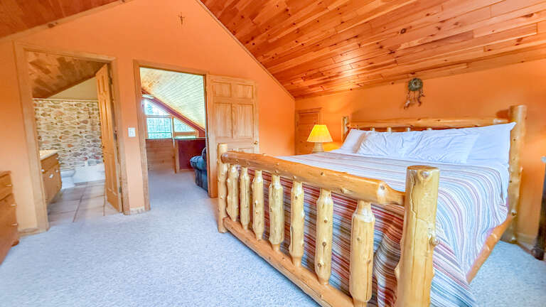 Drift off in your cozy loft bedroom with handcrafted log furnishings, vaulted wood ceilings, and the perfect blend of rustic charm and comfort.