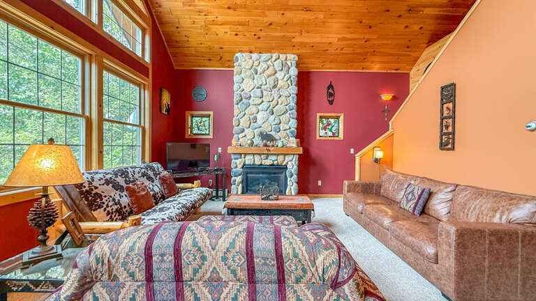 Gather around the stunning stone fireplace and sink into inviting leather sofas, surrounded by soaring wood-paneled ceilings and tall windows that bathe your vacation retreat in natural light.