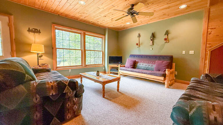 Relax into the cabin charm of your living space, where natural wood ceilings and playful fishing decor set a welcoming, peaceful tone for your stay.