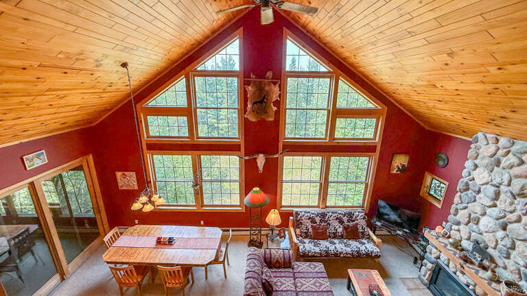 Soaring wood-beamed ceilings and expansive windows frame the natural beauty outside. Your cozy stone fireplace invites relaxation, while the spacious open layout gives you room to gather and unwind together.