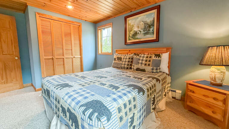 Unwind in your cozy bedroom, where warm pine ceilings and a plush quilt invite restful nights. Natural light filters through the window, and rustic mountain charm makes every moment feel like a true retreat.