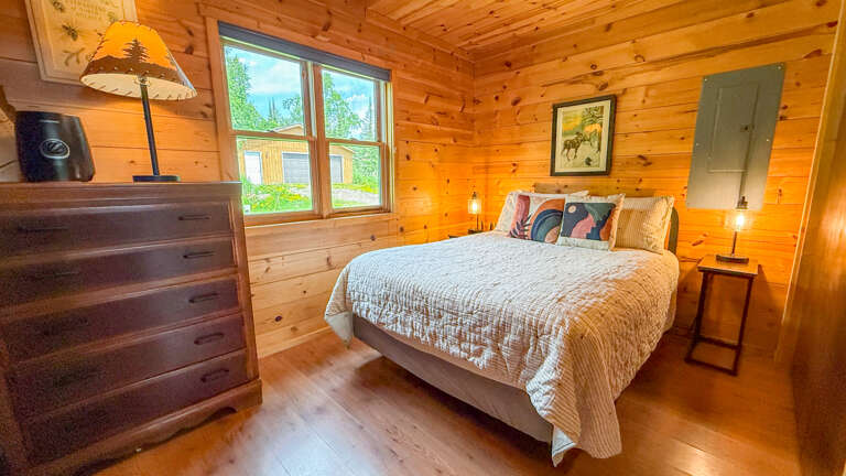 Cozy up in this charming bedroom with warm wood walls and restful mountain views. Soft lighting and handcrafted touches make your retreat feel like home.