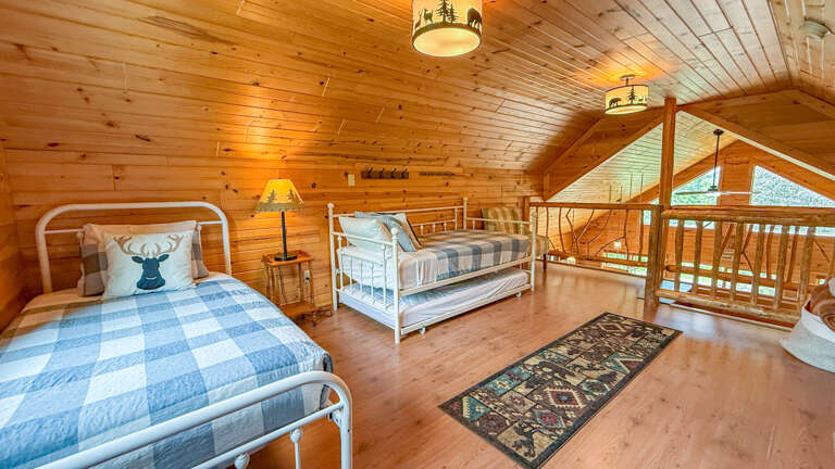 Cozy up in this charming loft bedroom with rustic wood beams and plaid bedding. You'll love the woodland-themed dÃ©cor and warm ambiance of your cabin retreat.