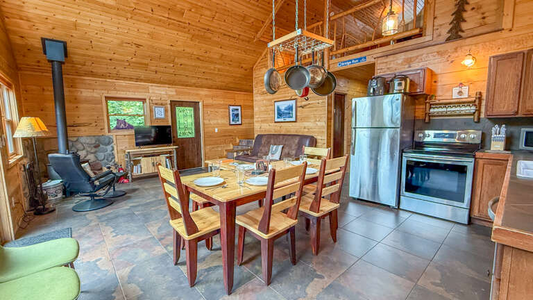 Your cozy cabin retreat features a full kitchen with modern appliances, a welcoming dining table for six, and a wood-burning fireplace to warm those mountain evenings.