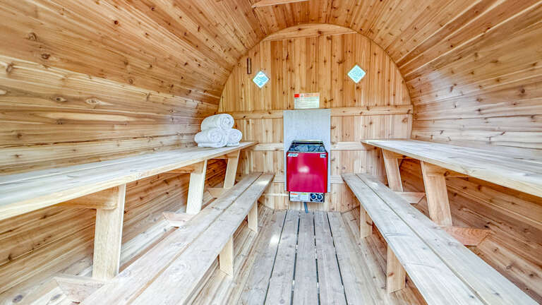 A traditional barrel-style sauna with tiered wooden benches and a modern heater, offering a warm, soothing retreat after an active day.