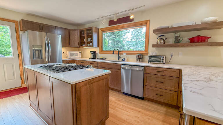 Cook up a feast in your spacious kitchen with modern appliances, granite counters, and open shelving for your favorite cookware, all bathed in natural light from the forest beyond.