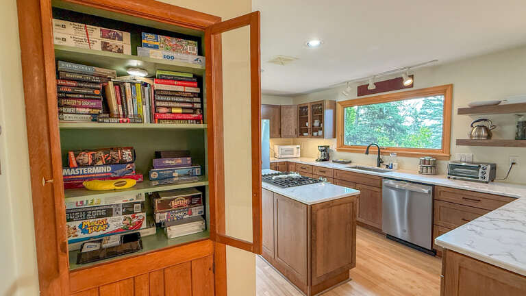 Gather around the spacious kitchen island and whip up your favorite meals with modern appliances and marble counters. Natural light pours through the large window, while board games await your evenings in.
