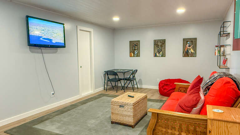 Unwind in your own cozy lounge with plush beanbag seating, a warm wood futon, and unique wildlife art adding character to the space.