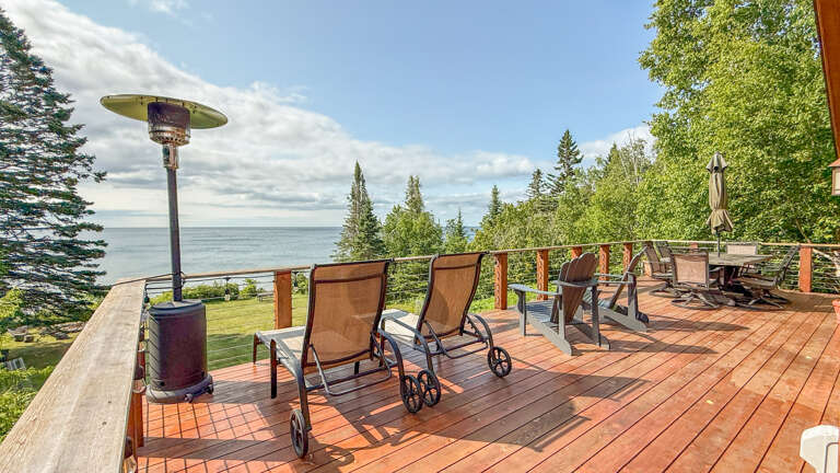 Spacious waterfront deck with lounge chairs, dining area, and outdoor heater—perfect for soaking up lake views and fresh air.