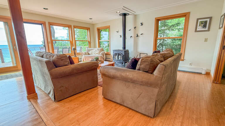 Settle into plush comfort and soak in stunning water views through every window. The cozy fireplace adds warmth, while natural light spills across gleaming hardwood floorsâyour perfect retreat by the sea.