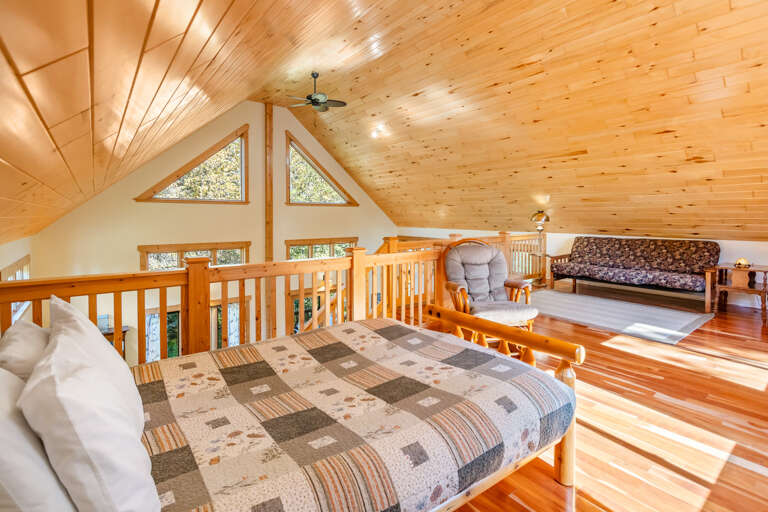 Curl up under the soft quilt and let the sunlight streaming through the triangular windows warm your loft retreat. The gleaming wood ceiling and rocking chair make this cozy nook your perfect hideaway.