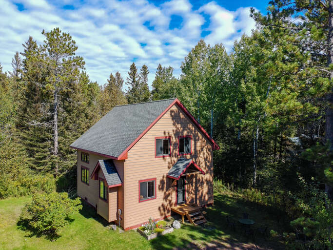 Charming two-story retreat nestled among towering pines and lush greenery, offering a peaceful woodland setting with ample natural beauty surrounding the property.
