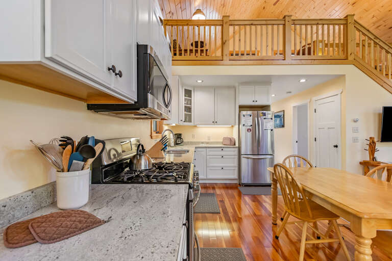 Your fully equipped kitchen has everything you need to prepare memorable meals—from the gas stove and spacious counters to cozy dining seating and charming wood accents overhead.
